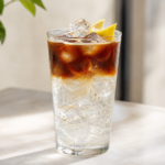 Espresso Tonic im hohen Glas mit Eis, deutlicher Kaffeeschicht und Zitronengarnitur